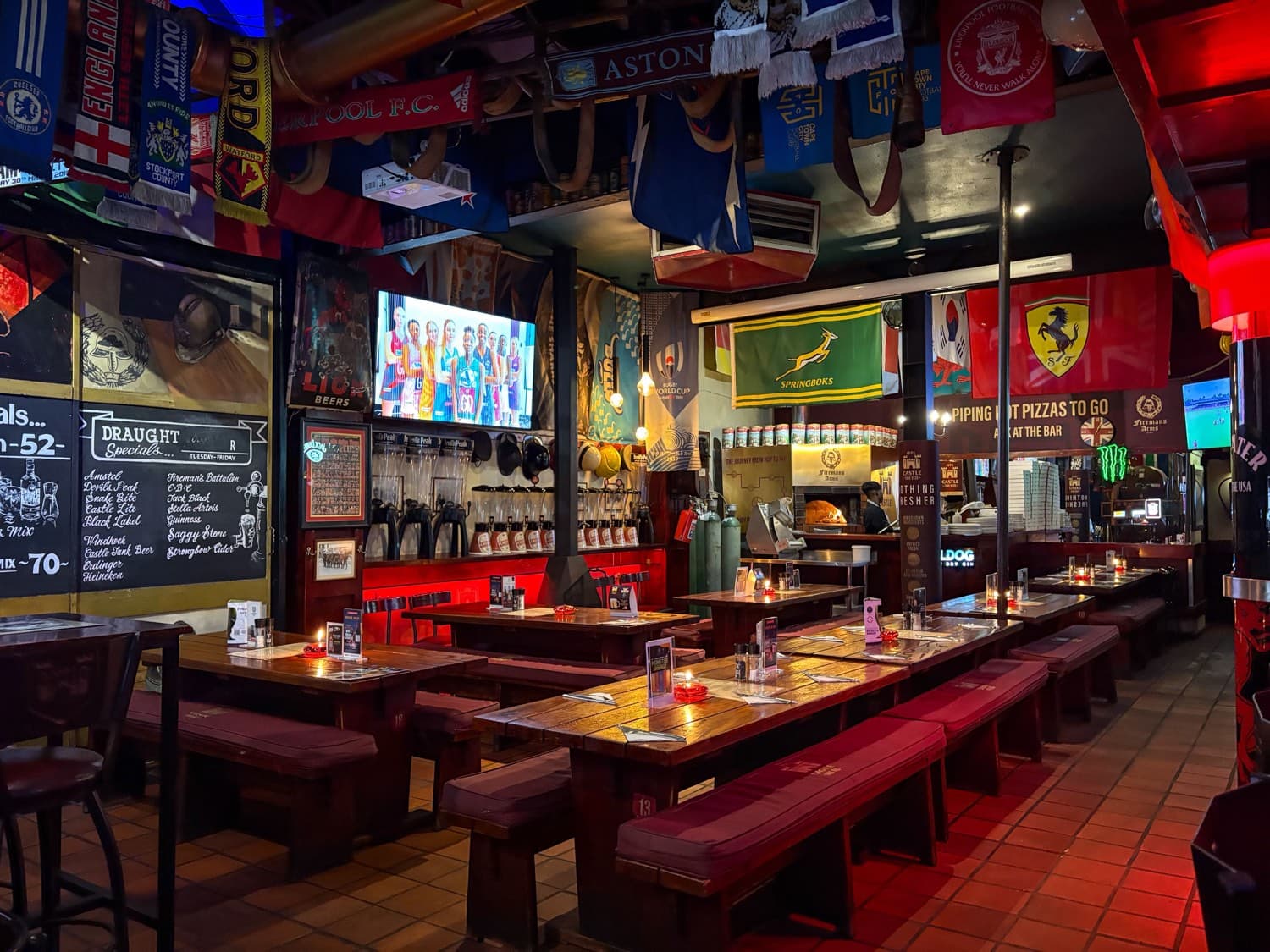 A sports bar with a game on the television and flags from around the world on the walls