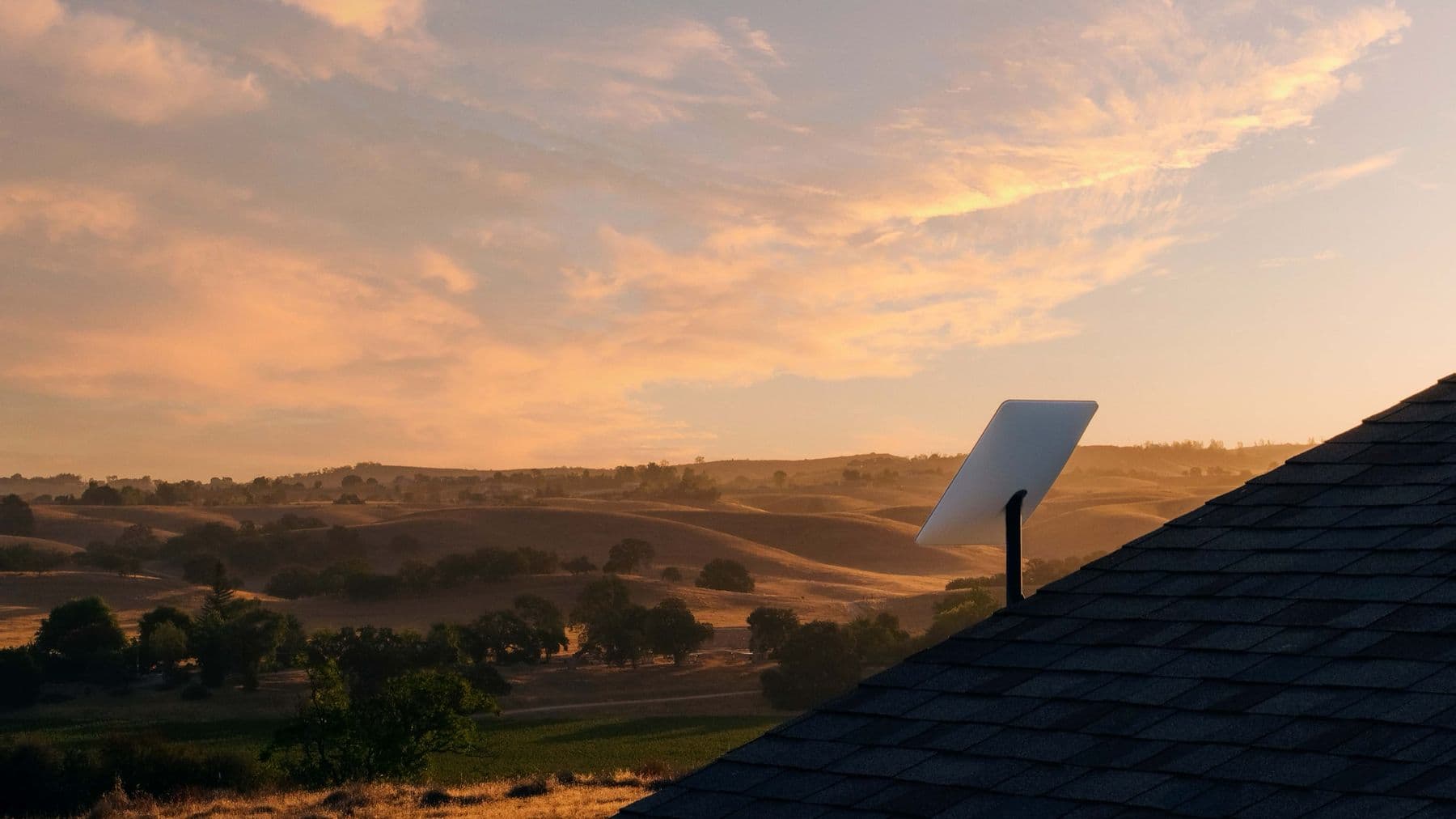 A Starlink dish installed on a building in open country